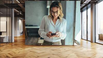 Smiling businesswoman using smartphone in office Wall mural