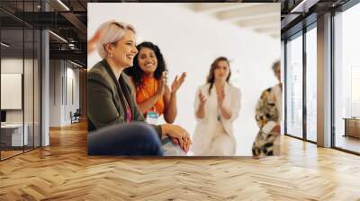 Smiling businesswomen applauding their colleague in an office Wall mural