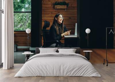 Smiling female entrepreneur having a video call in a coworking space Wall mural