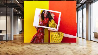 Smiling women with empty photo frame Wall mural