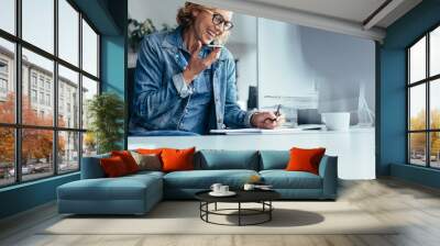 Smiling young businesswoman working at her desk Wall mural