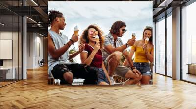 Smiling young friends eating ice-cream outdoors Wall mural