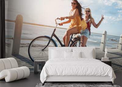 Stylish young female friends on a bicycle Wall mural