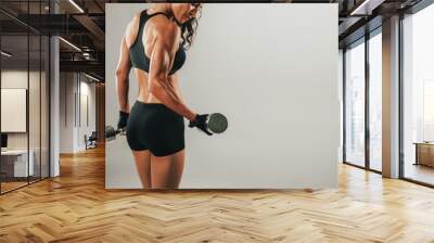 Sweating female athlete lifting dumbbell Wall mural