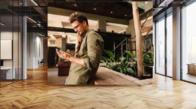 Thoughtful businessman using mobile phone in office lobby Wall mural