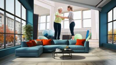 trainer helping senior woman on bosu balance training platform Wall mural