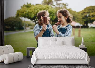 Twin sisters enjoying eating candy icecream Wall mural