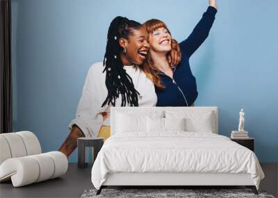 Two cheerful best friends laughing and having fun while embracing each other Wall mural