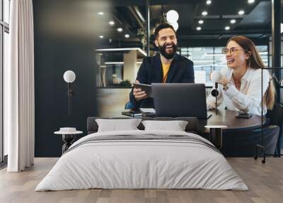 Two happy young businesspeople working together Wall mural