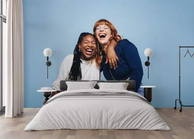 Two interracial best friends laughing and having a good time together in a studio Wall mural