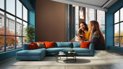 Two women sitting at a cafe and smiling Wall mural