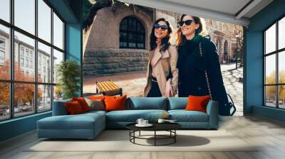 Two women walking outdoors and smiling Wall mural