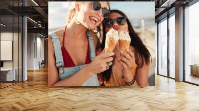 two young women eating an ice cream together Wall mural