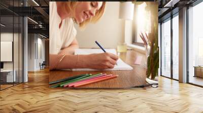 Woman coloring an adult coloring book with pencils Wall mural