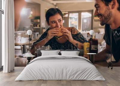 Woman eating burger with friends at restaurant Wall mural