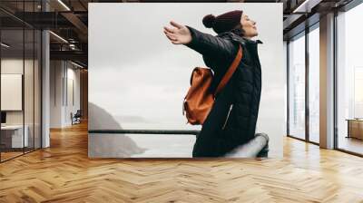 Woman happily breathing in the fresh sea air Wall mural