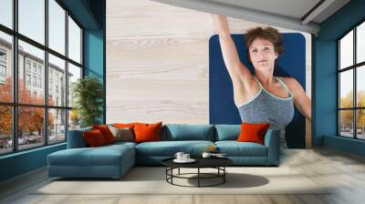 Woman lying and stretching on exercise mat Wall mural