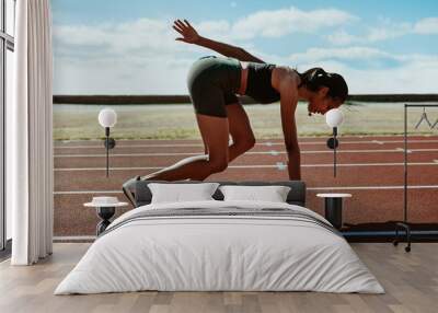 Woman runner at the start line taking position on a running trac Wall mural