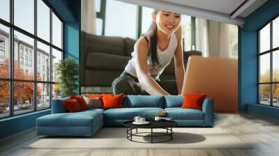 Woman using laptop while exercising at home Wall mural