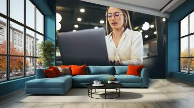 Woman working on a laptop in a modern workspace Wall mural