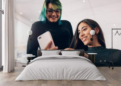 Women at salon looking at mobile phone Wall mural