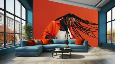 Young, fashionable black woman celebrates and enjoys herself with a hair flip, dancing and smiling in a vibrant studio setting Wall mural