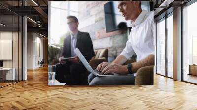 Young businessman working on laptop at corporate meeting Wall mural