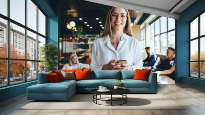 young businesswoman holding a smartphone in a co-working space Wall mural