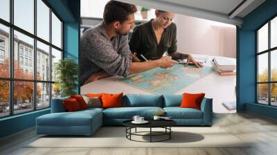 Young couple exploring the world map.. Wall mural