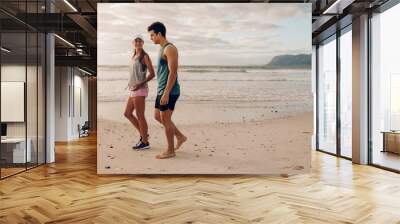 Young couple on walking along the shore Wall mural