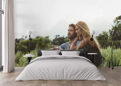 Young couple sitting together in meadow Wall mural