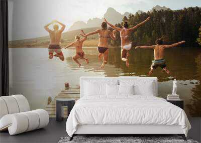 Young friends jumping into lake from a jetty Wall mural