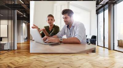 Young man and woman at home using laptop Wall mural