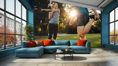 Young man and woman stretching in the park Wall mural