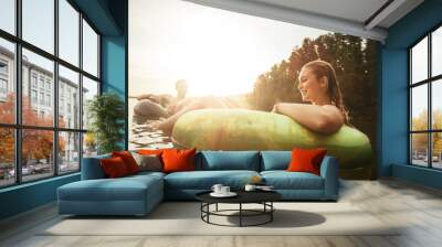 Young woman floating in an innertube at sunset Wall mural