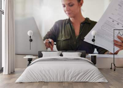 Young woman with documents working on laptop Wall mural