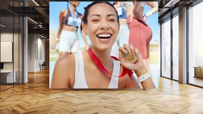 Closeup portrait of mixed race athletic woman showing gold medal from competing in sports event. Smiling fit active latino athlete feeling proud after winning running race. Wall mural