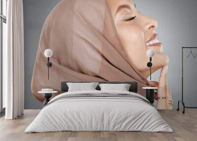 Face, beauty or skincare with a woman muslim wearing a hijab in studio on a gray background for natural wellness. Cosmetics, happy and skin with an Islam female in a headscarf to promote health Wall mural