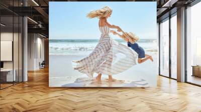 Happy mother swinging and spinning cute daughter in circles by the arms at the beach. Playful, energetic and joyful kid having fun while bonding with mom on sunny summer vacation outdoors Wall mural