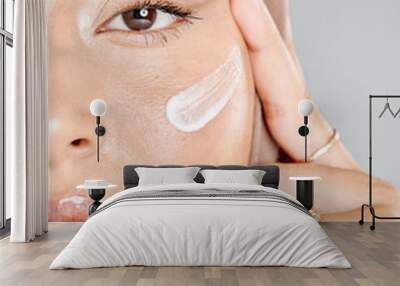 Portrait of a young Muslim woman wearing a hijab or headscarf applying a cream moisturizer on her flawless skin while showing her eyelash extensions while. Applying cosmetics to maintain healthy skin Wall mural