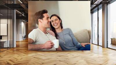 Filling their home with love and laughter. Shot of a happy young couple relaxing together at home. Wall mural