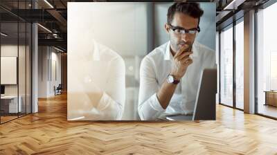 Mmm...I wonder. Cropped shot of a handsome young businessman looking thoughtful while working on his laptop in the office. Wall mural