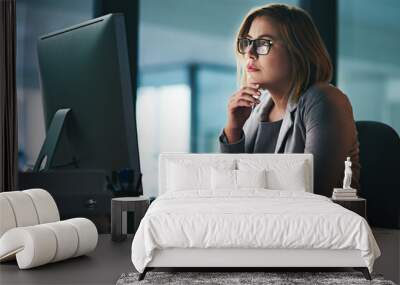 She thinks through every challenge carefully. Shot of a young businesswoman working late on a computer in an office. Wall mural