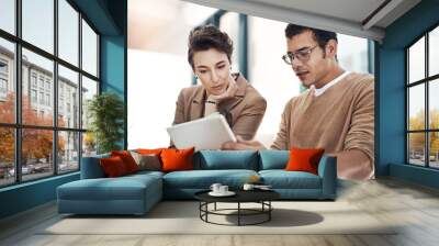 The online world holds all the answers. Shot of two businesspeople working together on a digital tablet in an office. Wall mural