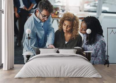 Business growth is a team task. a group of colleagues using a laptop together in a modern office. Wall mural