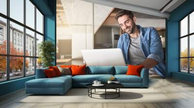 For productivity, just log in. Shot of a handsome young man using a laptop in a coffee shop. Wall mural