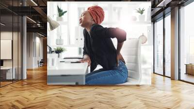 Her back is taking most of the strain. Cropped shot of an attractive young businesswoman holding her back in pain while sitting at her desk in the office. Wall mural