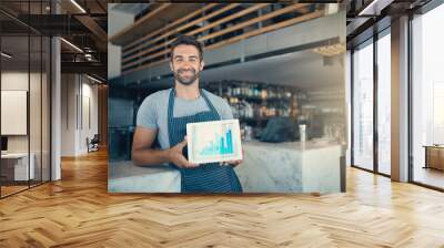 Investing your passion pays off. Portrait of a young man holding a digital tablet with a graph on the screen at a coffee shop. Wall mural