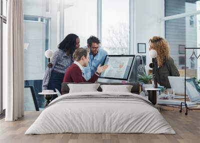 Nothing boosts productivity like teamwork. Shot of a group of colleagues using a computer together in a modern office. Wall mural