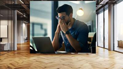 Putting his career first and his health second. Shot of a young businessman experiencing stress during a late night at work. Wall mural